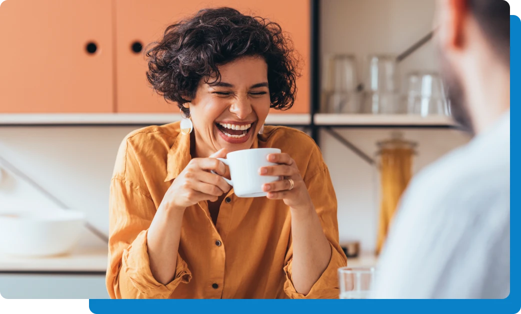 woman laughing with man drinking coffee in kitchen